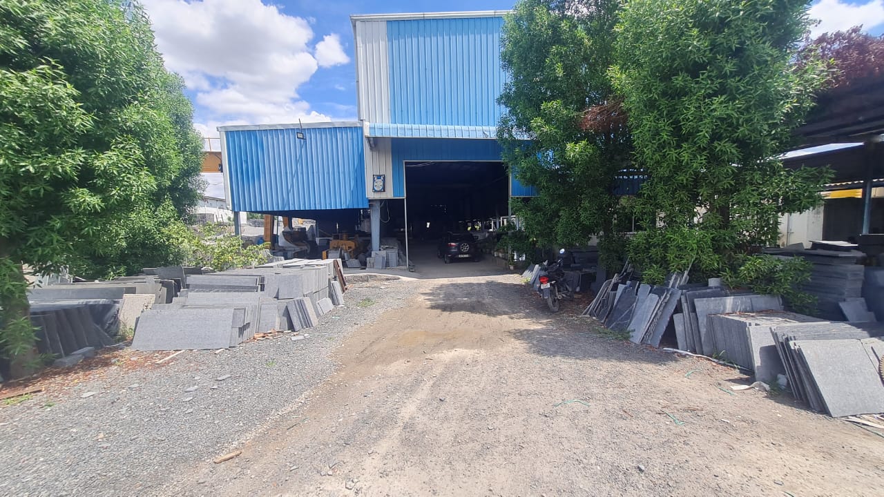 Blue-clad main shed with granite slabs stacked along the entrance drive
