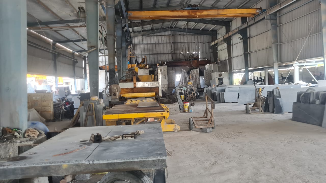 Inside the cutting shed: cutting machines and cut granite pieces under an overhead crane