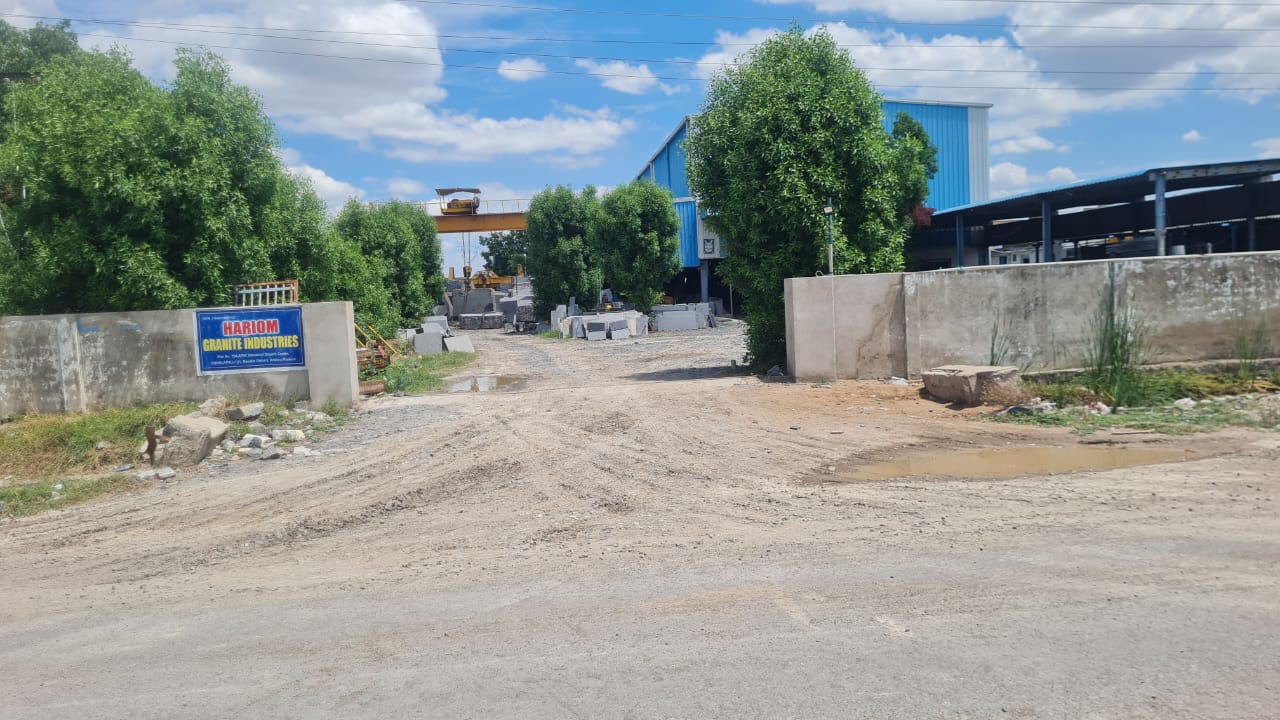 Site gate with the Hariom Granite Industries sign, gantry crane visible in the distance