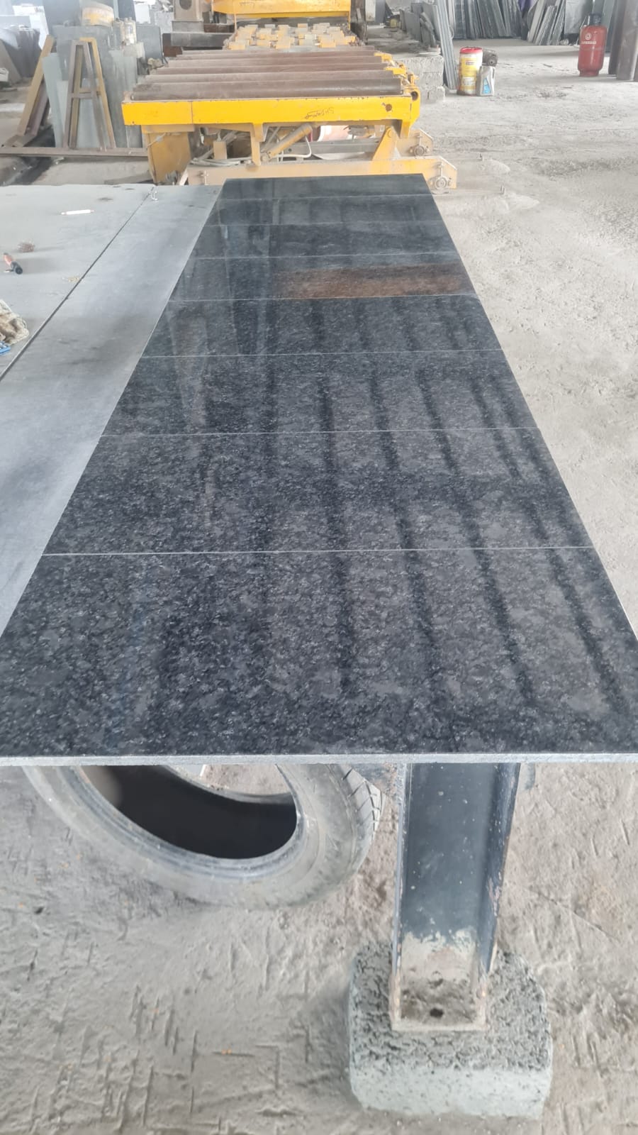 A run of polished Steel Grey granite tiles on a steel stand in the cutting shed