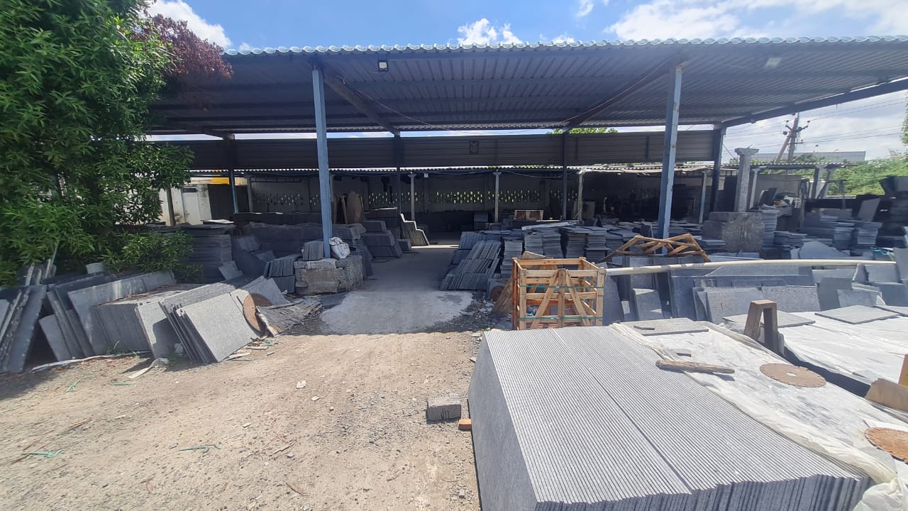 Covered finished-goods yard with stacks of cut granite slabs and a wooden export crate
